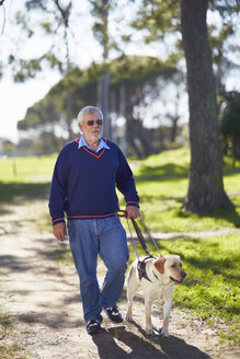 Visually impaired man walking with his guide dog in a park - ZEF000986