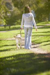 Sehbehinderte Frau geht mit Blindenhund in einem Park spazieren - ZEF000868