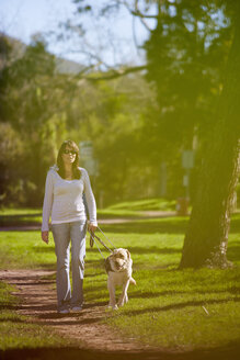 Visually impaired woman walking with guide dog in a park - ZEF000864
