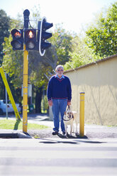 Ein sehbehinderter Mann wartet mit seinem Blindenhund an einer Fußgängerampel - ZEF000997