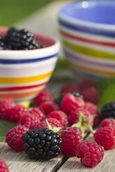 Bowl of blackberries and raspberries on wooden table - YFF000247