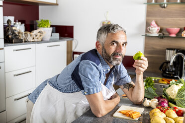 Österreich, Mann in Küche isst Apfel - MBEF001243