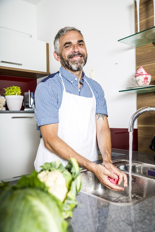Österreich, Mann in Küche wäscht Gemüse, lizenzfreies Stockfoto