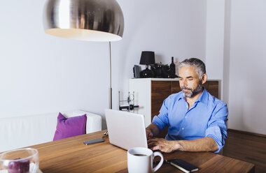 Businessman working with laptop at home office - MBEF001286