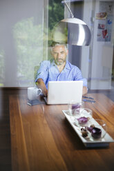 Geschäftsmann arbeitet mit Laptop im Büro zu Hause - MBEF001184