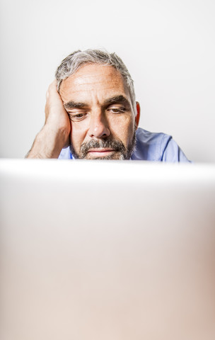 Porträt eines langweiligen Geschäftsmannes mit Laptop im Heimbüro, lizenzfreies Stockfoto