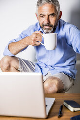Potrait eines Geschäftsmannes bei einer Kaffeepause in seinem Büro zu Hause - MBEF001189
