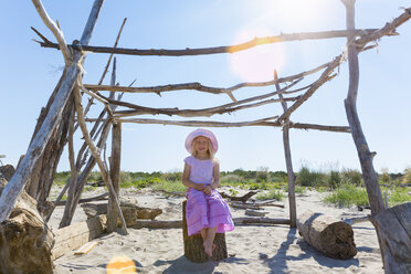 Italien, Venetien, Mädchen sitzt in selbstgebauter Strandhütte - HSIF000338