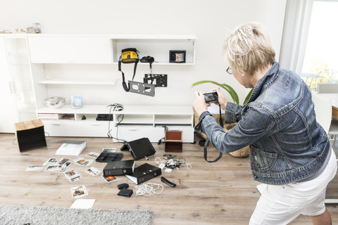 Frau fotografiert das Chaos nach einem Einbruch, als sie in ihr Einfamilienhaus zurückkehrt, lizenzfreies Stockfoto