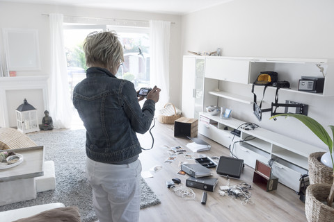 Frau fotografiert das Chaos nach einem Einbruch, als sie in ihr Einfamilienhaus zurückkehrt, lizenzfreies Stockfoto