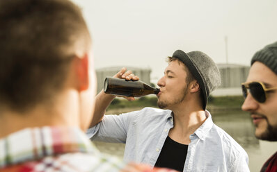 Eine Gruppe von Freunden trinkt Bier am Flussufer - UUF001872