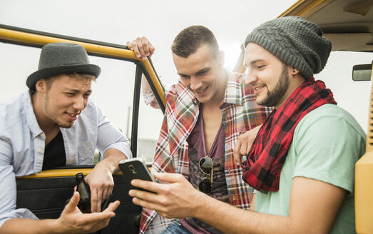 Gruppe von Freunden mit Mobiltelefon an einem Auto - UUF001876