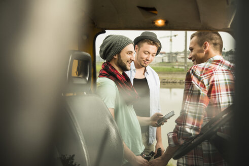 Gruppe von Freunden mit Mobiltelefon an einem Auto - UUF001877