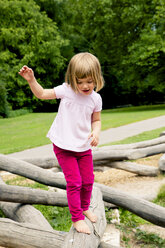 Kleines Mädchen auf Spielplatz balanciert auf Baumstamm - LVF001880