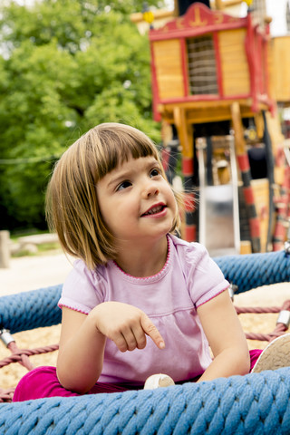 Kleines Mädchen auf Spielplatz in Nestschaukel, lizenzfreies Stockfoto