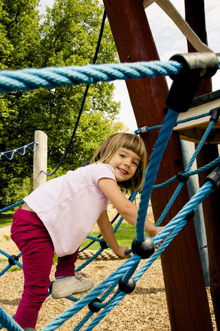 Kleines Mädchen klettert auf Spielplatz, lizenzfreies Stockfoto