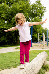 Kleines Mädchen auf Spielplatz balanciert auf Baumstamm - LVF001888