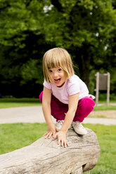 Little girl on playground crouching on log - LVF001890