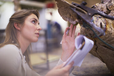 Junge Frau in der Werkstatt eines Bildhauers, der sein Kunstwerk prüft - ZEF000367