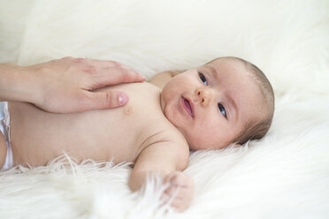 Kleines Mädchen auf einem Schafsfell liegend mit der Hand der Mutter auf dem Bauch - ROMF000018