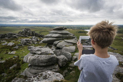 UK, Cornwall, Junge fotografiert Landschaft in Bodmin Moor mit seinem digitalen Tablet, lizenzfreies Stockfoto