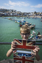 UK, Cornwall, lächelnder Junge, der in St. Ives ein Selfie mit seinem digitalen Tablet macht - PAF000975