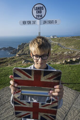 Vereinigtes Königreich, Cornwall, Junge, der mit seinem digitalen Tablet ein Selfie vor dem Wegweiser in Land's End macht - PAF000963