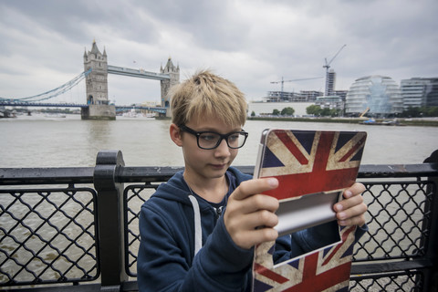 Großbritannien, London, Junge fotografiert mit digitalem Tablet an der Tower Bridge, lizenzfreies Stockfoto