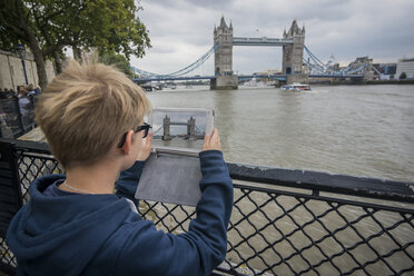 Großbritannien, London, Junge fotografiert mit digitalem Tablet an der Tower Bridge - PAF000977