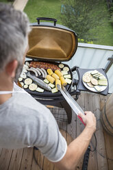 Mann beim Grillen auf seinem Balkon - MBEF001275