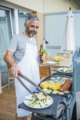 Mann beim Grillen auf seinem Balkon - MBEF001277