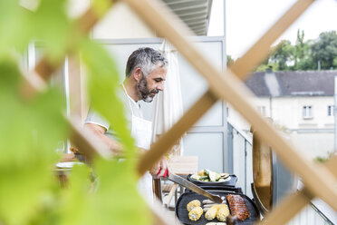 Mann beim Grillen auf seinem Balkon - MBEF001278