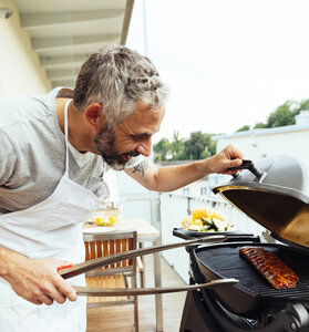 Mann beim Grillen auf seinem Balkon - MBEF001282