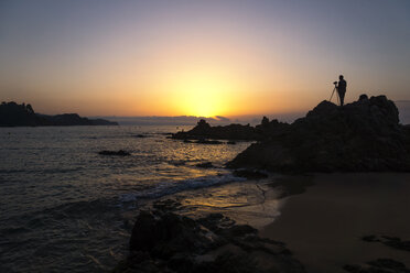 Spain, Catalonia, Lloret de Mar, Platja de Santa Christina, Silhouette of a photographer at sunrise - PU000086