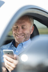 Businessman with cell phone in car - UUF001927