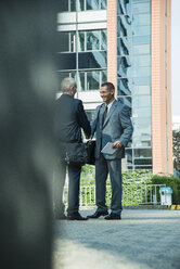 Two businessmen shaking hands outside office building - UUF001948