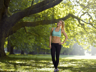 Germany, Young athletic woman standing under a tree - MAD000006