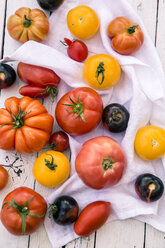 Verschiedene Heirloom-Tomaten auf weißem Holz und Stoff - SARF000852