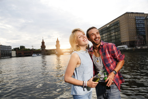 Deutschland, Berlin, Junges Paar genießt den Sonnenuntergang an der Spree, lizenzfreies Stockfoto