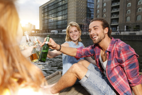 Germany, Berlin, Friend sitting at Spree river, drinking beer - FKF000681