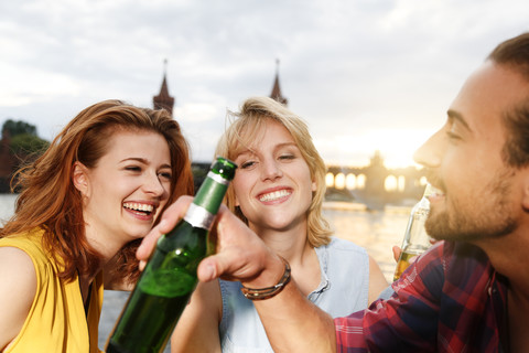 Germany, Berlin, Friend sitting at Spree river, drinking beer stock photo