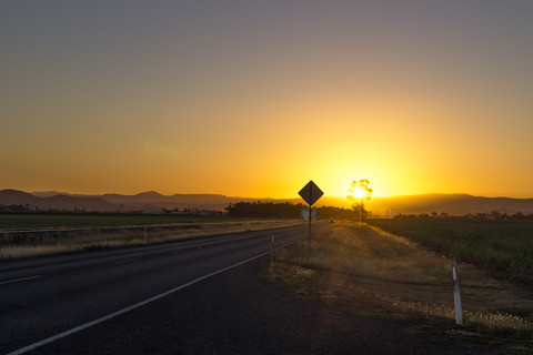 Australien, Queensland, Straße mit Bergkette bei Sonnenaufgang, lizenzfreies Stockfoto