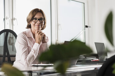 Portrait of smiling businesswoman at desk - UUF001905