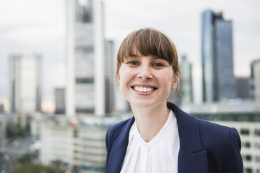 Deutschland, Hessen, Frankfurt, Porträt einer lächelnden Geschäftsfrau vor einer Skyline - FMKYF000518