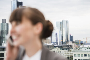 Deutschland, Hessen, Frankfurt, lächelnde Geschäftsfrau beim Telefonieren vor der Skyline - FMKYF000520