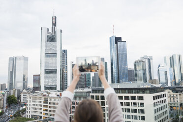 Deutschland, Hessen, Frankfurt, Frau fotografiert die Skyline mit Mini-Tablet - FMKYF000522