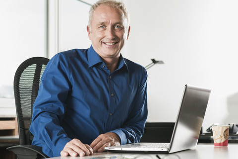 Porträt eines lächelnden Geschäftsmannes am Schreibtisch, lizenzfreies Stockfoto