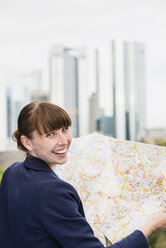 Deutschland, Hessen, Frankfurt, Porträt einer lächelnden Frau mit Stadtplan - FMKYF000542
