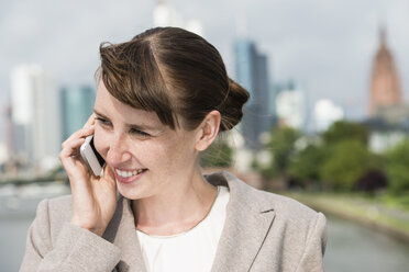 Germany, Hesse, Frankfurt, portrait of smiling businesswoman telephoning with smartphone - FMKYF000553