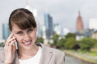 Germany, Hesse, Frankfurt, portrait of smiling businesswoman telephoning with smartphone - FMKYF000554